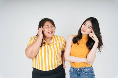 Düşünceli iki Asyalı kadın beyaz arka planda izole edilmiş bir şey düşünüyor..