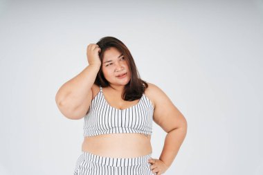 Stresli ve baş ağrısı çeken beyaz spor sutyenli şişman bir kadın beyaz arka planda doğru izolasyona bakıyor..