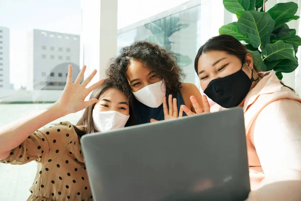 Maske takan bir grup kadın evde bilgisayar laptopuyla dolaşıyorlar..