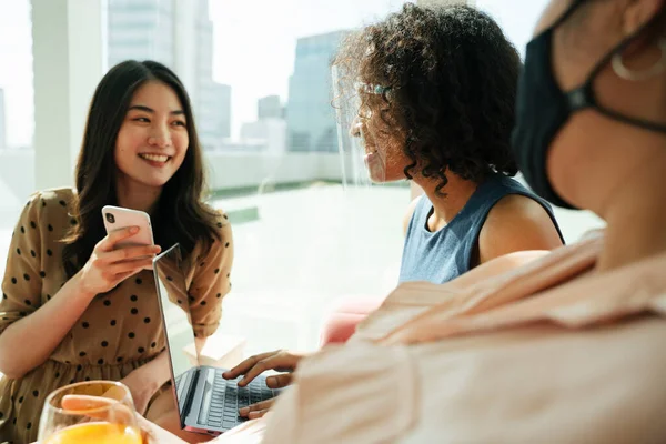Afrikalı kadın bir odada insanlarla konuşurken yüz maskesi takıyor..