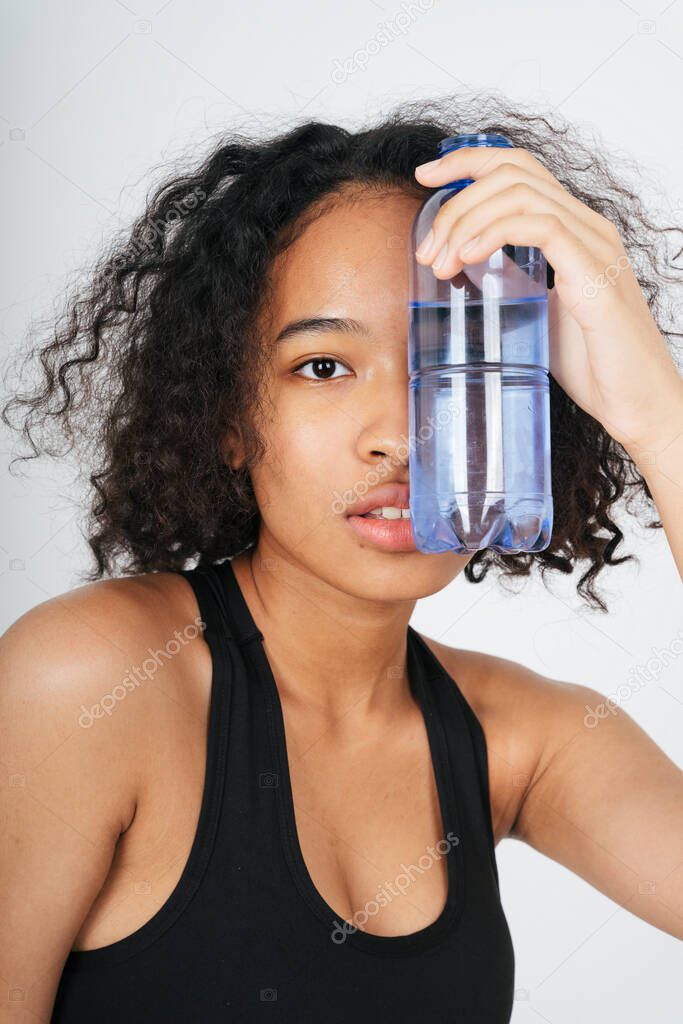 Portrait of mixed race african and thai woman holding a bottle of water.