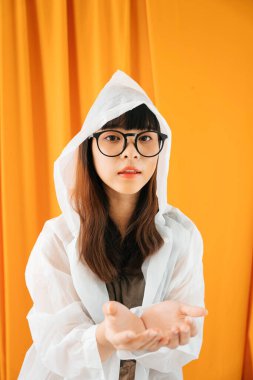 Beyaz yağmurluk ve gözlük takan genç Asyalı kadın ürünleri koymak için iki elini gösteriyor..