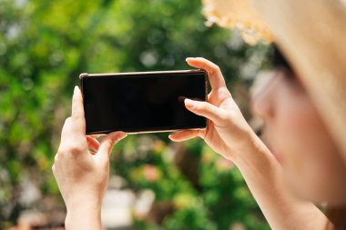 Gezgin kadın tatil köyünde açık havada akıllı telefon kullanıyor. Reklam için boş alan.