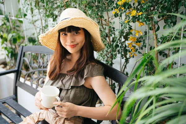 亚洲年轻的女旅行家戴着草帽 喜欢在户外喝咖啡 — 图库照片