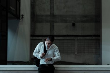 Dazlak adam kız arkadaşını beklerken barikata yaslanmış kol saatine bakıyor..