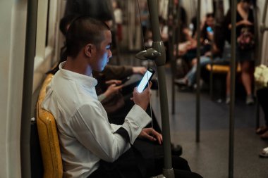 Bir adam gökyüzünde sarı bankta oturuyor ve gizli telefon kullanıyor..