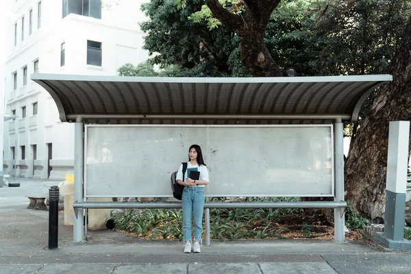 Aranyos Lány Fehér Pólóban Könyvekkel Karjában Áll Buszmegállóban Buszra Vár — Stock Fotó