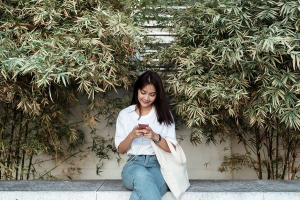 Cute Girl White Shirt Sitting Little Bamboo Garden Using Phone — Stock Photo, Image