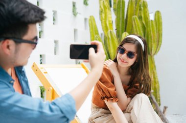 Erkek arkadaşı, kız arkadaşının akıllı telefonuyla fotoğrafını çekiyor..