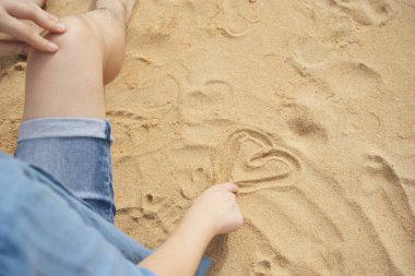 Yalnız adam kuma kalp sembolü çiziyor..