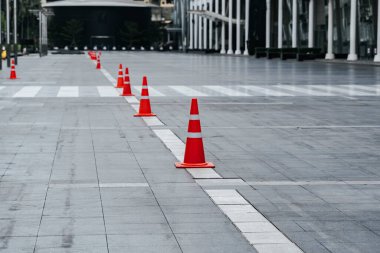 Kırmızı ve beyaz çizgili trafik konileri ve yolda barikat bandı..