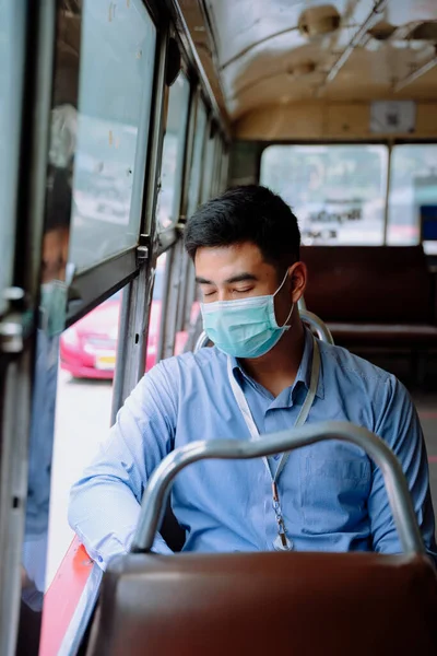 Asian business man wear mask travel by a bus transportation in Bangkok