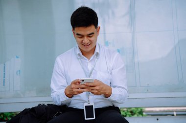 Otobüs durağında akıllı telefon kullanan neşeli iş adamı..