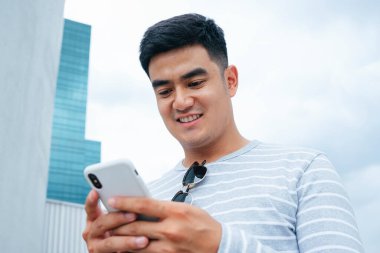 Şehirde akıllı telefon kullanan Asyalı adamın portresini kapat..