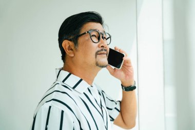 Beyaz yakalı yaşlı bir adam telefonda konuşuyor..