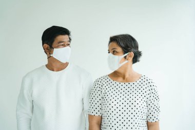 Beyaz gömlekli yaşlı çift portresi. Arka planda maske takıyor..