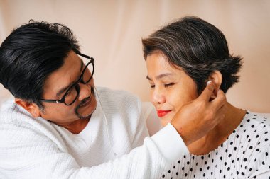 Romantik son sınıf Asyalı çift koltukta oturup aynı kulaklıkla müzik dinliyor..