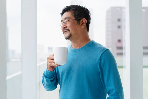 穿着蓝色长袖衬衫 戴着眼镜 拿着咖啡的老年老人的画像 — 图库照片