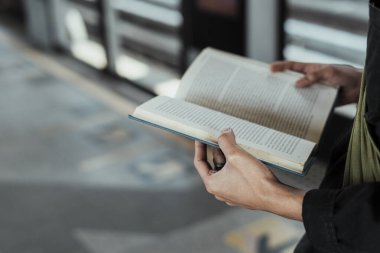 Arrowa 'nın arka plan olarak kullanıldığı Skytrain İstasyonu' nun zemininde, bir adamın ellerinde açılmış bir kitabın görüntüsü..