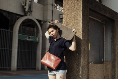 Koyu mavi polo tişörtlü kadın güneş ışığında ayakta duruyor yazın omuzunda uzun tahtayı taşıyor..