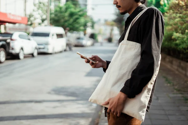 Vystřižený Obrázek Smartphonu Mužské Ruce Bílou Plátěnou Taškou Rameni — Stock fotografie