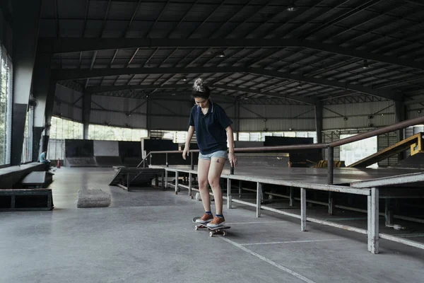 穿着深蓝色马球衫的女人在滑板田里玩耍的时候会滑倒在脚底的长板上 — 图库照片