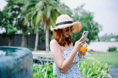 Havuz başında akıllı telefon kullanan Asyalı güzel bir gezgin..