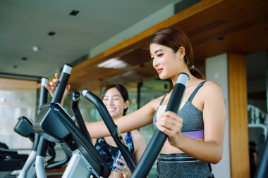 Güzel, sağlıklı bir kadın spor salonunda antrenörle makinede çalışıyor..