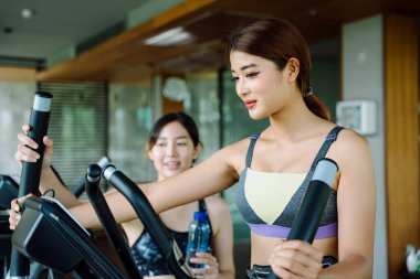 Güzel, sağlıklı bir kadın spor salonunda antrenörle makinede çalışıyor..