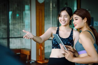 Güzel, sağlıklı bir kadın spor salonunda antrenörle egzersiz programı hakkında konuşuyor..