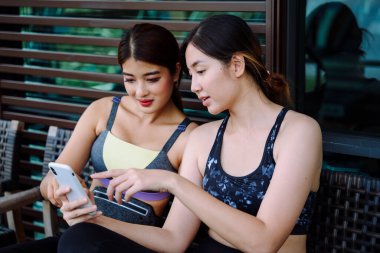 Güzel, sağlıklı kadınlar spor yaptıktan sonra dinlenme odasında akıllı telefon kullanıyorlar..