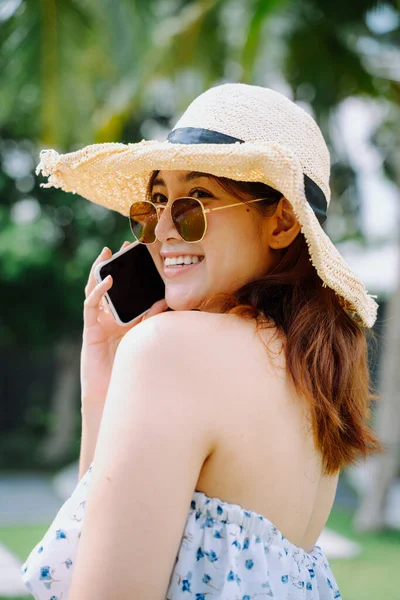야외에서 스마트폰을 사용하여 선글라스와 모자를 여행하는 아름다운 이시아 — 스톡 사진