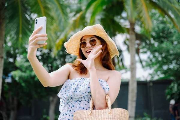 아름다운 아시아 여행자들이 스마트폰을 가지고 여행을 하면서 모자와 선글라스를 — 스톡 사진