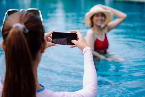 美丽的亚洲女性游客喜欢在游泳池里用智能手机拍照 — 图库照片