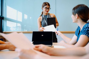 Asyalı iş kadını konferans odasında dijital bilgisayarla strateji planını açıkladı.