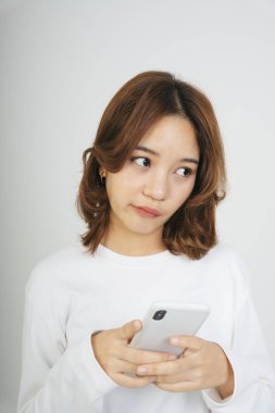 Akıllı telefonlu genç Asyalı kadın beyaz arka planda izole edilmiş..