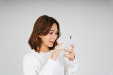 Akıllı telefonlu genç Asyalı kadın beyaz arka planda izole edilmiş..