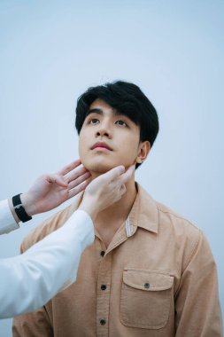 Asyalı genç adam hastanede doktorla sağlık kontrolü yapıyor..