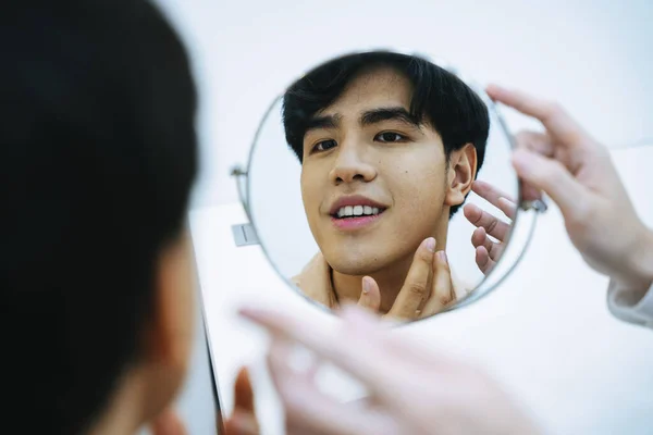 アジアの若者は自分自身を見て鏡の中で顔の治療について美容師からアドバイスを取る — ストック写真