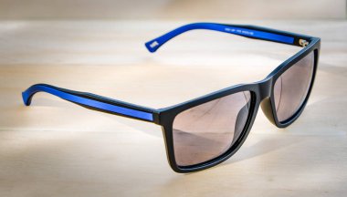 güneş gözlüğü açık ahşap yüzeyüzerinde mavi çizgili siyah.