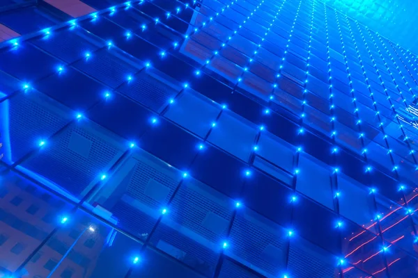 Fachada de vidrio espejada azul del edificio. Iluminación de lámparas azules. Perspectiva desde abajo hacia arriba . —  Fotos de Stock