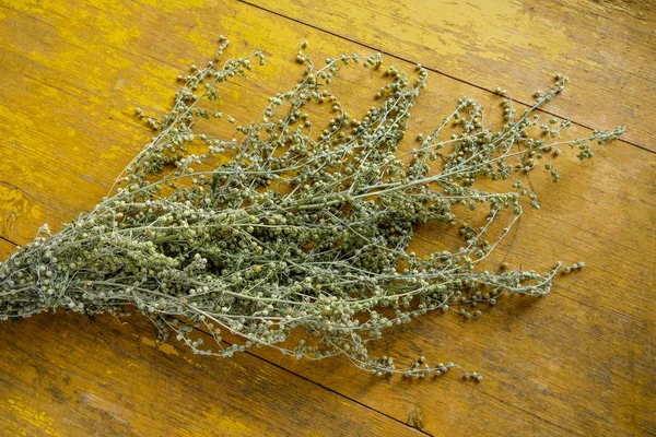 Droog boeket van alsem planten op een achtergrond van oude gele planken. Uitzicht vanaf boven. — Stockfoto