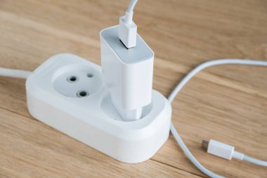 Elektrik hattına bağlı akıllı telefonlar için USB kablosu olan şarj aleti. Ahşap arkaplan.