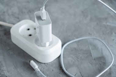 Elektrik hattına bağlı akıllı telefonlar için USB kablosu olan şarj aleti. Gri arkaplan.