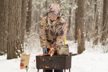 Kadın bir karla kaplı ormanda ateş et hazırlar