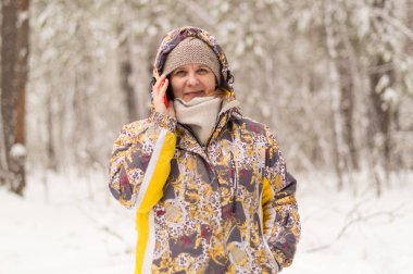 Bir kadın bir telefon numarasını çevirir. Hücresel iletişim kullanımı ile konuşuyor. Kış orman kentin eteklerinde.