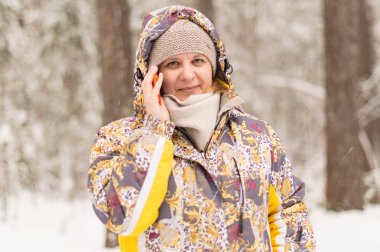 Bir kadın bir telefon numarasını çevirir. Hücresel iletişim kullanımı ile konuşuyor. Kış orman kentin eteklerinde.