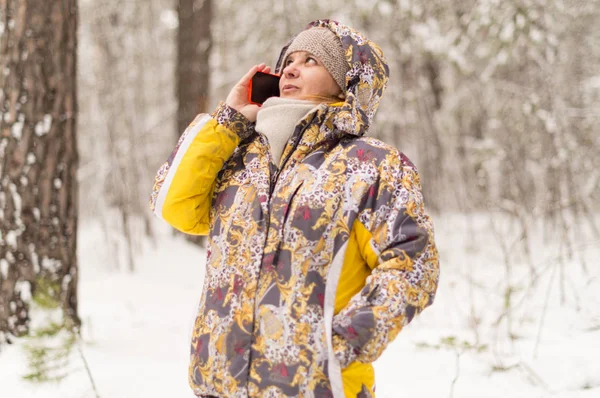 A woman dials a phone number. Talking with the use of cellular communication. Winter forest on the outskirts of the city.