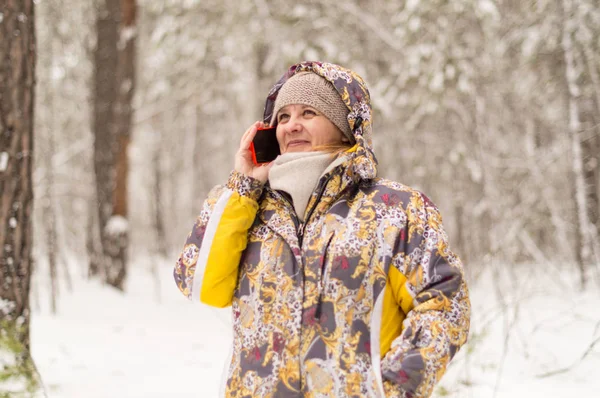 A woman dials a phone number. Talking with the use of cellular communication. Winter forest on the outskirts of the city.