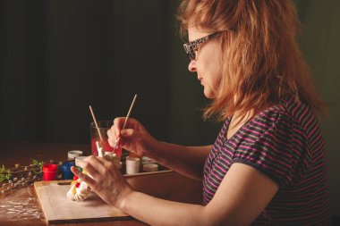 Sanatçı bardaklarda tasarım çalışmaları gerçekleştirir. Bahar, sıcak ruh hali. Masaya willow ve Lila yeşil çiçek yaprakları ile dalları vardır. Çok renkli Paskalya tavşanı.